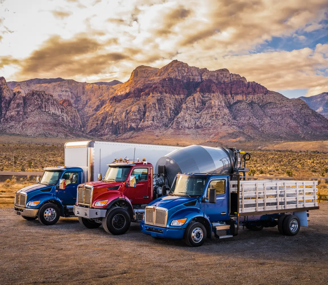 A fleet of three trucks wait under a cloudy sky